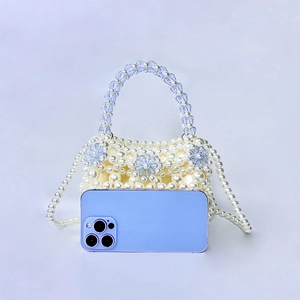 Macro shot of handmade mini pearl bag with blue crystal flowers and a long shoulder strap