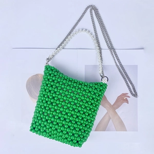 Detail of green handmade beaded bucket bag with white pearl handle and silver chain strap