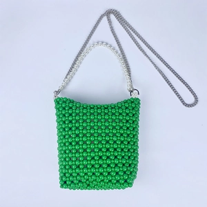 Detail of green beaded bucket bag with white pearl handle and silver chain strap