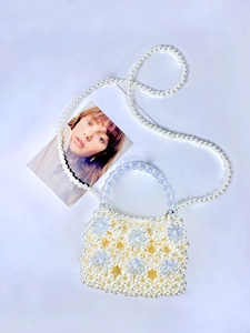 Detailed weave of white pearls and light blue crystal flowers on a handmade tote bag