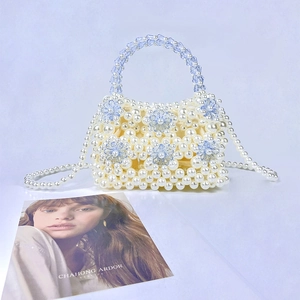 Detail of handmade beaded pearl handbag with blue crystal floral pattern on white background