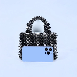 Detail of handmade beaded pearl handbag in metallic grey with smartphone for size reference