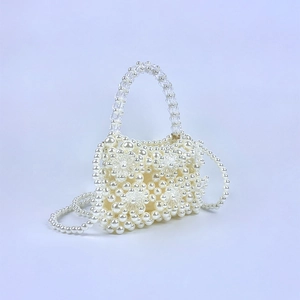 Detail of beaded pearl handbag showing acrylic floral patterns and crystal handles