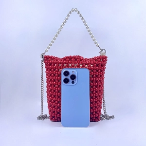 Detail of red beaded bucket bag with pearl handle and size comparison to smartphone