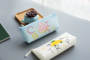 Close-up of silicone pencil cases with watermelon and pineapple prints in a study setting