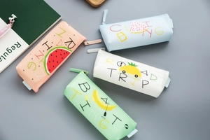 Flat lay of four colorful silicone fruit pencil cases with cute summer themed illustrations