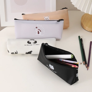 Detail of four colorful silicone cat pencil cases on desk with stationery and cozy lamp