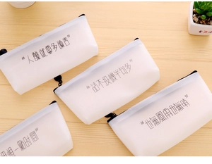 Close-up of frosted semi-transparent pencil cases with Chinese text on a wooden desk