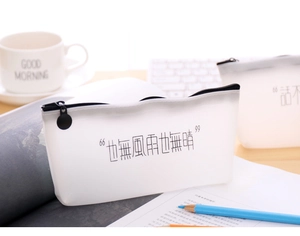 Close-up of a white translucent pencil case with black calligraphy on a desk setup