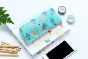 Detail of mint green canvas pencil case with flamingo prints and stationery desk accessories