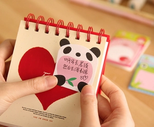 Close-up of red coil notebook with cute panda sticky notes for 100-day schedule planning