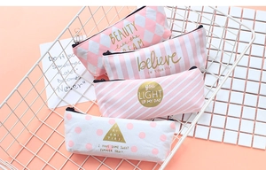 Close-up of pink striped canvas pencil cases with motivational gold lettering in a basket