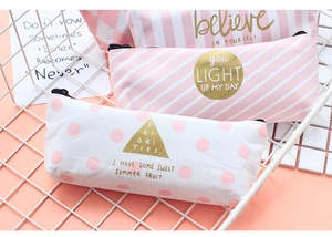 Detailed view of pink canvas pencil cases with striped and polka dot patterns in a metal bin