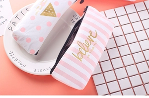 Close-up of pink striped and polka dot canvas pencil cases with gold lettering