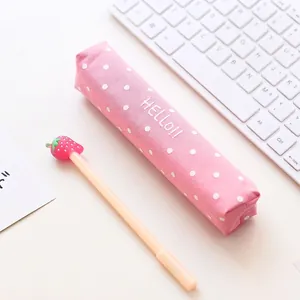 Roze canvas etui met witte stippen en een aardbeienpen op een wit bureau