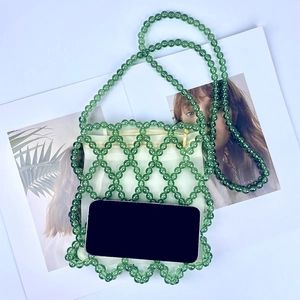 Dettaglio della borsa a secchiello verde con perline, sacchetto bianco e tracolla
