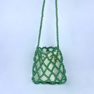 Dettaglio borsa a tracolla verde con perline intrecciate e interno in tela con coulisse