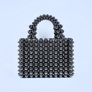 Detail of hand-woven bead bag showing metallic dark chrome finish and geometric structure