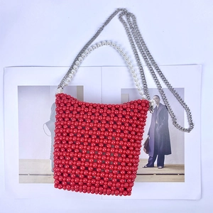Detail of red beaded crossbody bag with white pearl handle and silver chain strap