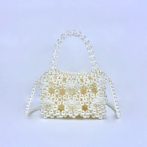 Macro detail of handmade beaded pearl bag with floral accents and crystal handles