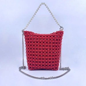 Detail of red beaded bucket bag featuring white pearl handle and silver chain strap
