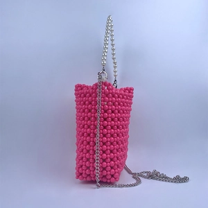 Macro detail of rose pink beaded bucket bag with pearl handle and silver chain strap