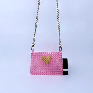 Detail of pink handmade beaded mini bag with gold heart pattern and chain strap