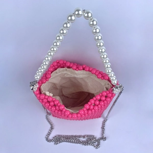 Close-up of rose pink beaded bucket bag with white pearl handle and silver chain strap