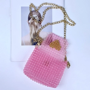 Detail of pink beaded mini bag with gold heart pattern and metallic crossbody chain