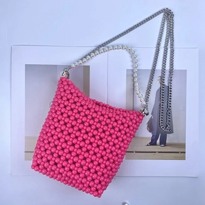 Detail of pink beaded bucket bag featuring pearl handle and silver chain strap