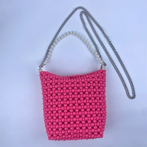 Close-up of pink beaded bucket bag with white pearl handle and silver chain strap