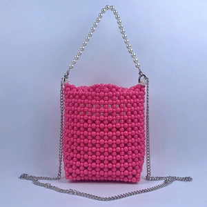 Detail of pink beaded bucket bag with white pearl handle and silver metal chain strap