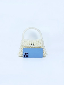 Handmade white pearl beaded handbag shown next to a smartphone for size reference
