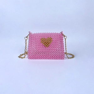 Detailed view of pink handmade beaded bag with a gold heart motif and chain strap