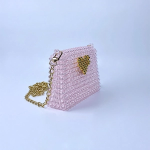 Detail of pink beaded mini bag with gold heart pattern and detachable chain strap