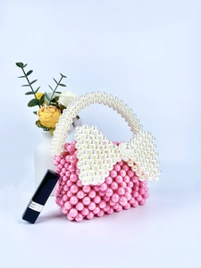 Mini borsa di perle rosa con un grande fiocco bianco e un manico in perle intrecciate