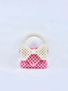 Dettaglio della mini borsa rosa fatta a mano con fiocco di perle bianche sul manico