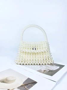 Handmade pearl beaded mini handbag in creamy white on a fashion magazine background
