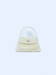 Detail of handcrafted white pearl woven handbag with trapezoid structure and handle