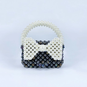 Dettaglio della borsa mini fatta a mano con perle viola e fiocco in perle bianche