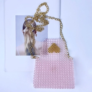 Detail of pink beaded mini bag with gold heart pattern and metal chain strap