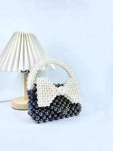 Borsa a mano in perle fatta a mano con fiocco bianco su sfondo azzurro chiaro