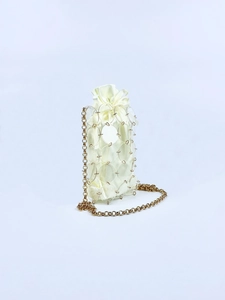 Detail of mini drawstring bag with shiny acrylic rings and golden chain strap