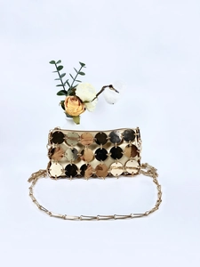 Dettaglio della borsa da sera con paillettes dorate e sottile tracolla a catena