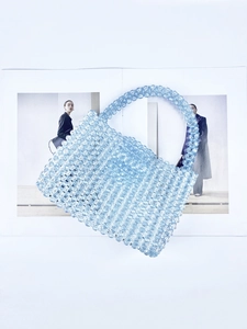 Close-up of light blue acrylic beads and woven texture of the handmade mini handbag