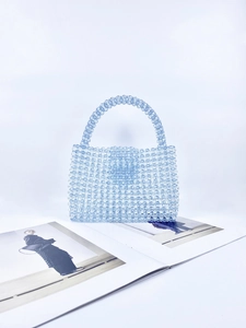 Detailed view of hand-woven light blue acrylic beads and smooth handle of the handbag