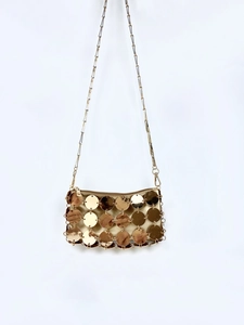 Dettaglio borsa di lusso con paillettes dorate, texture a dischi metallici e chiusura lampo