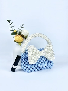 Dettaglio della borsa a mano in perle blu fatta a mano con decorazione a fiocco bianco