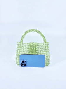 Detail view of light green acrylic beaded mini handbag with phone for size reference