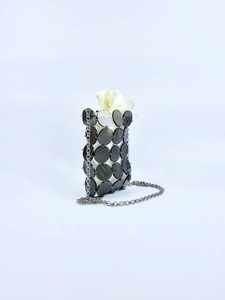 Detailed view of silver rings connecting black sequins on a mini bag with satin lining